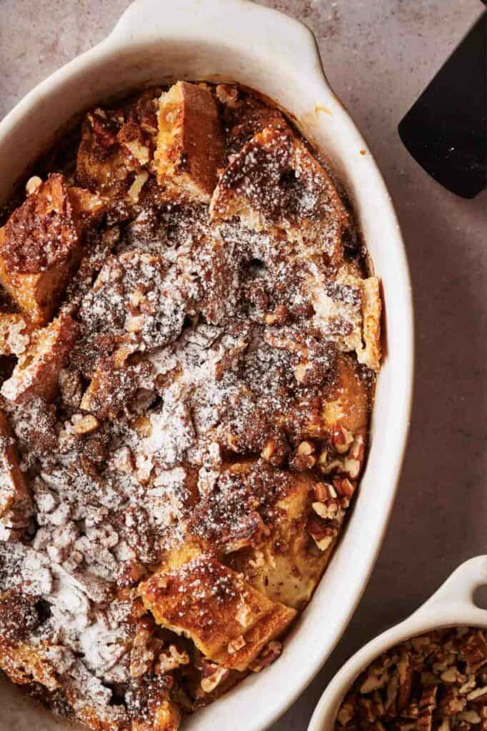 A French toast casserole with powdered sugar and nuts.