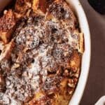A dish of French toast casserole with pecans and powdered sugar.