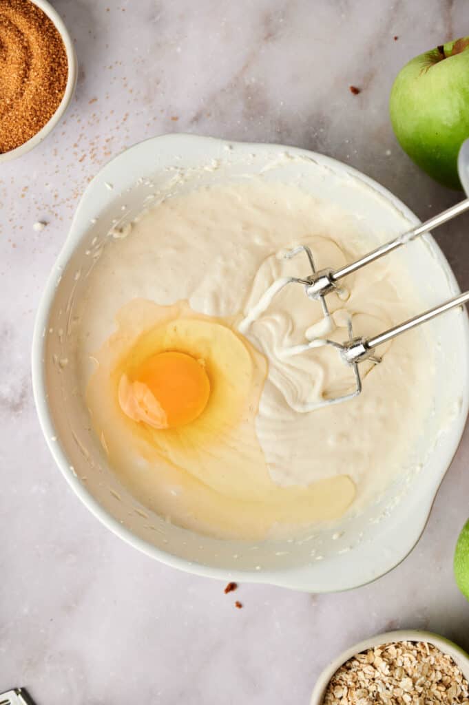 An egg in a bowl with apples and other ingredients.