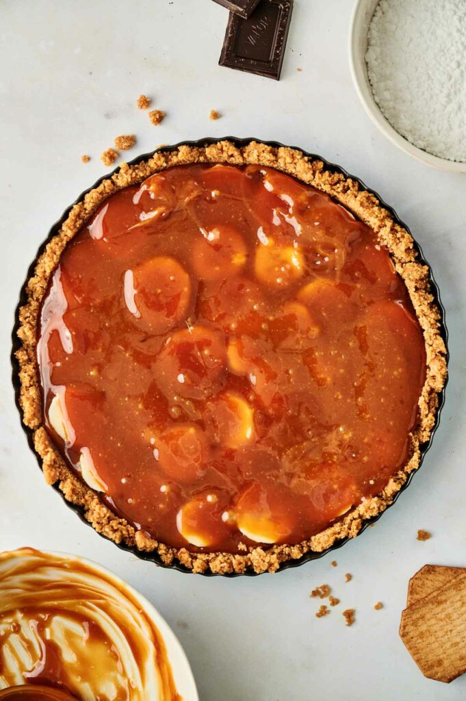 A pie with caramel and caramel sauce on a table.