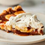 Banoffee pie on a plate with whipped cream.