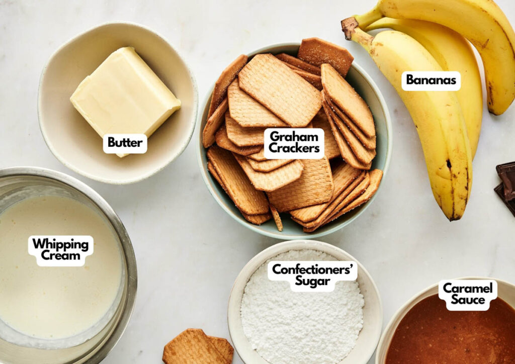 Bowls of butter, whipping cream, graham crackers, confectioners&rsquo; sugar, caramel sauce, and bananas arranged on a white surface hint at a rich dessert&mdash;perfect ingredients for an apple pie stuffed cheesecake or a delectable banana-caramel creation.