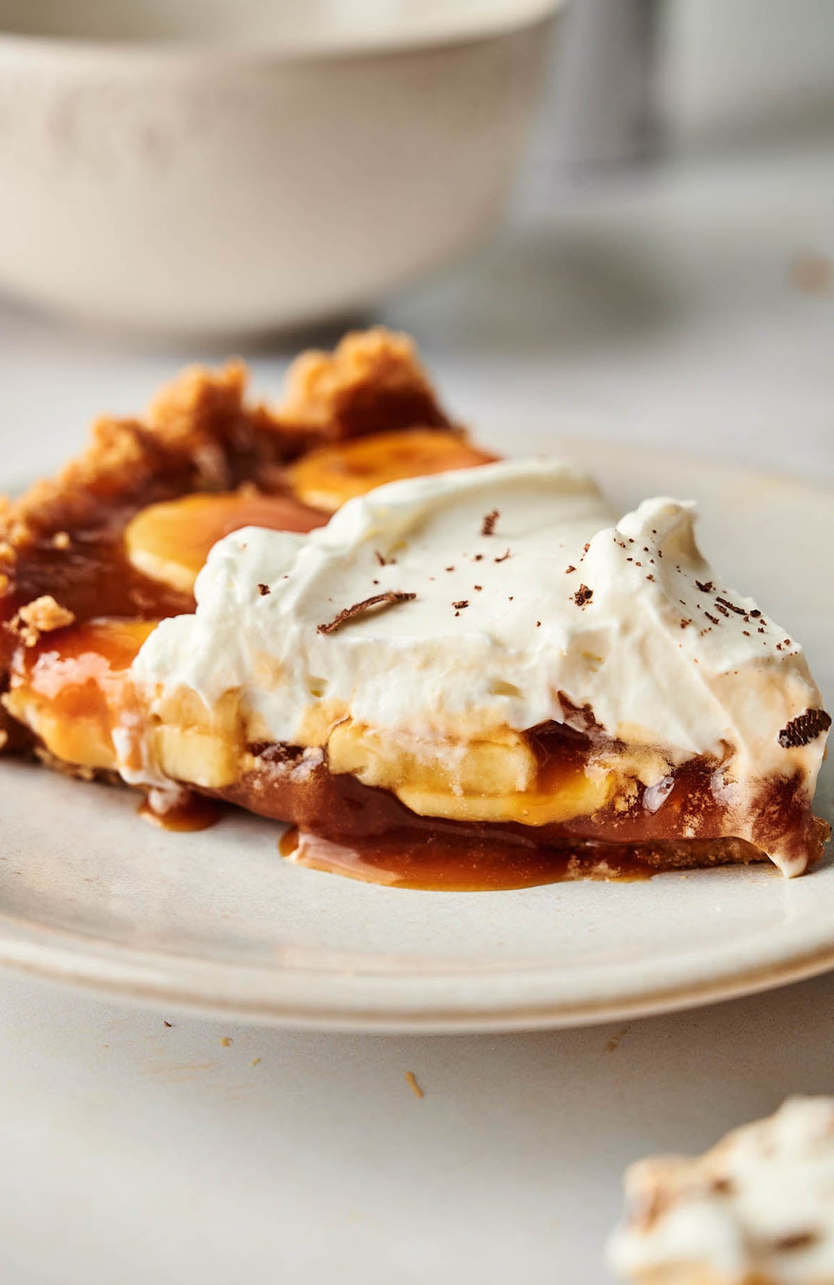 A slice of Banoffee pie with whipped cream and caramel on a plate.