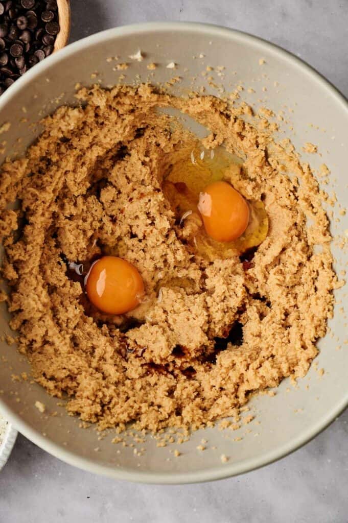 A bowl with two eggs and cookie batter.