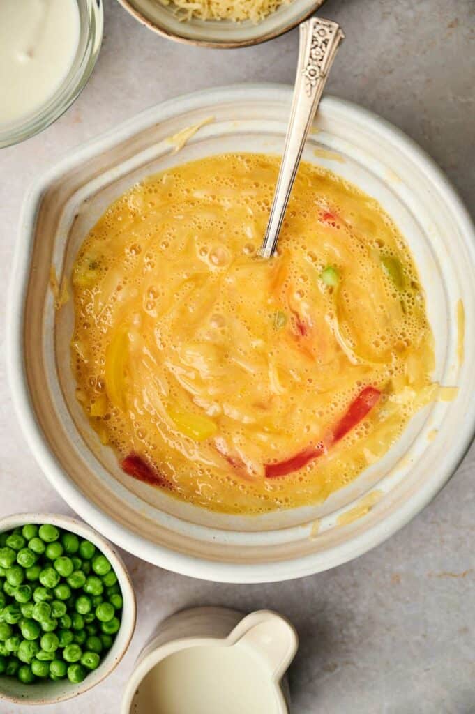 A bowl of egg mixture with peas.
