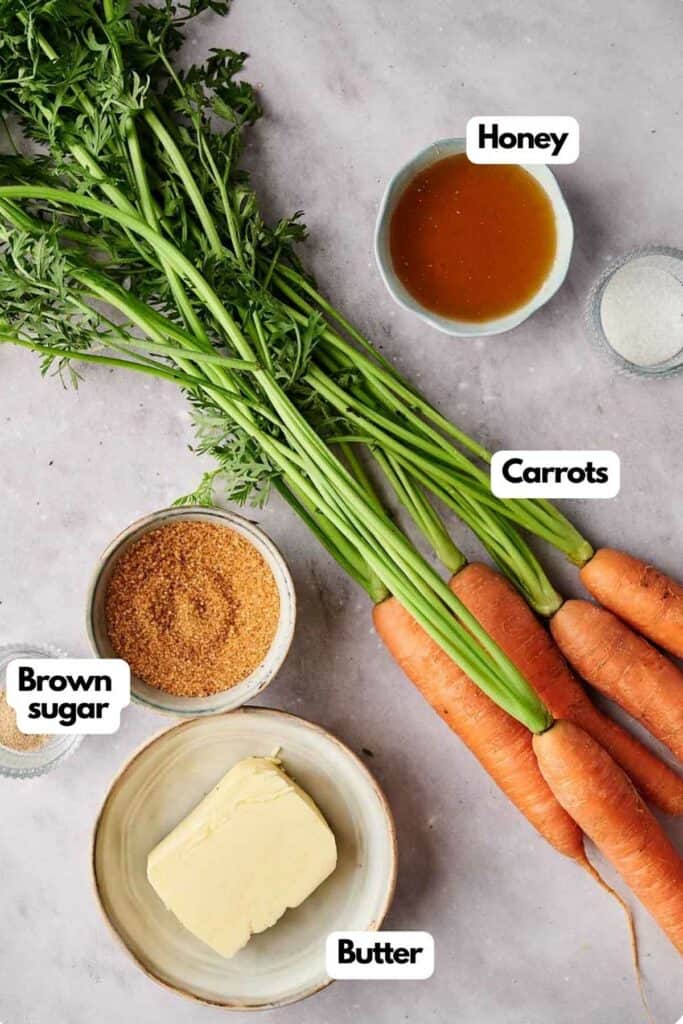 Carrots, honey, butter and other ingredients are shown on a white background.