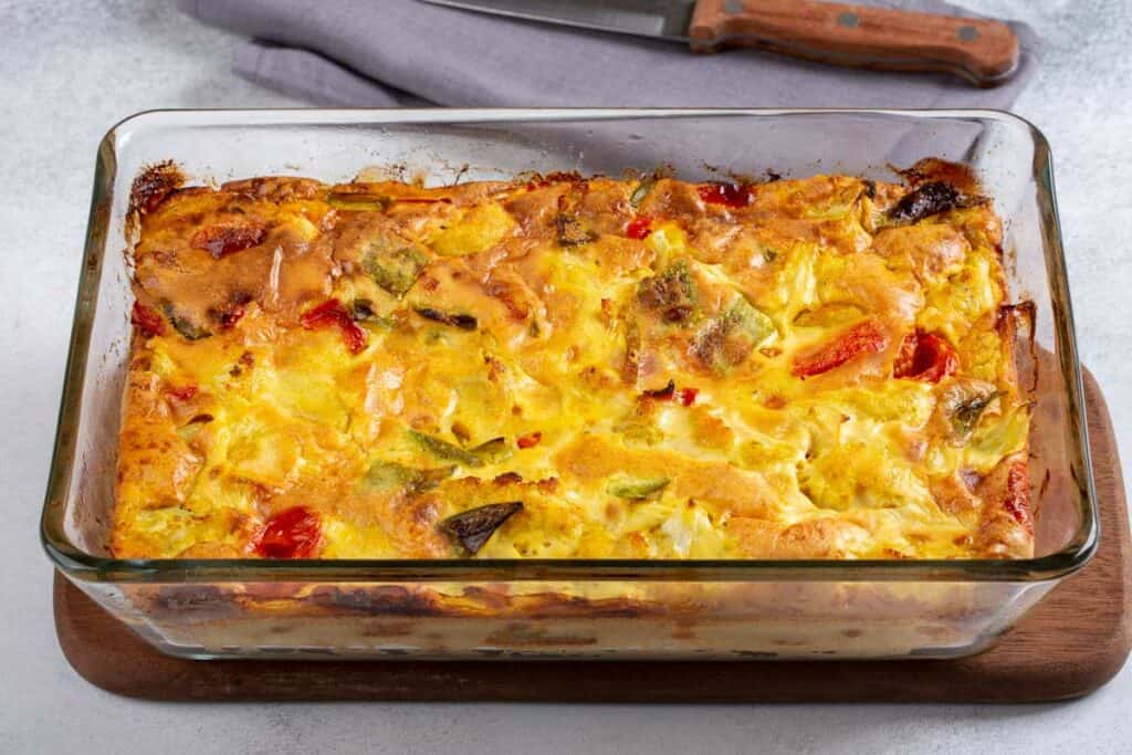 A casserole with eggs and vegetables in a glass dish.