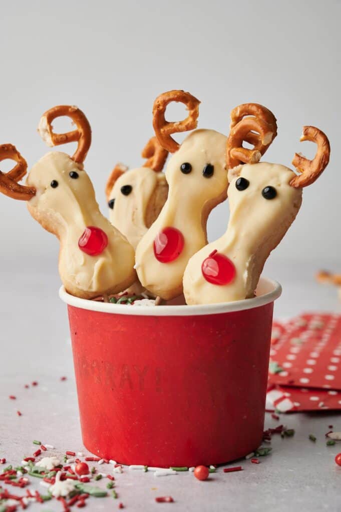 Reindeer cookie pops in a red cup.