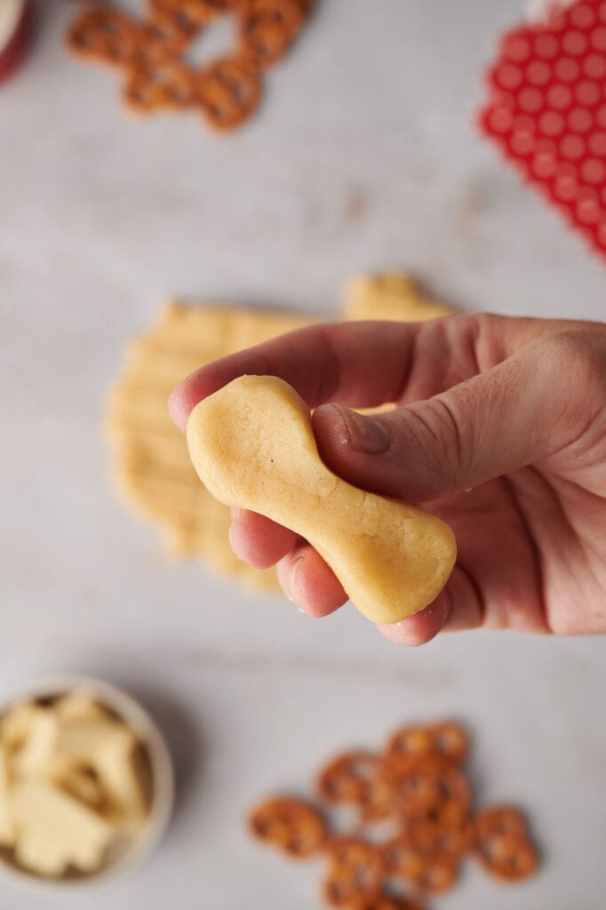 A person holding a cookie shaped like the body of a reindeer.