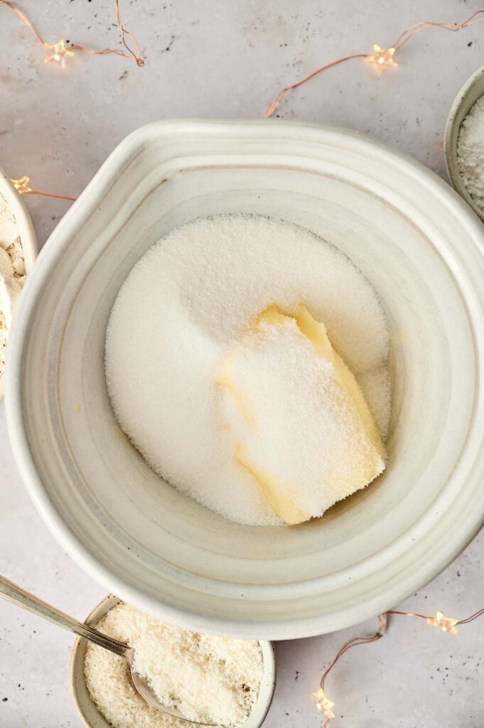 A bowl of flour, sugar and butter on a table.