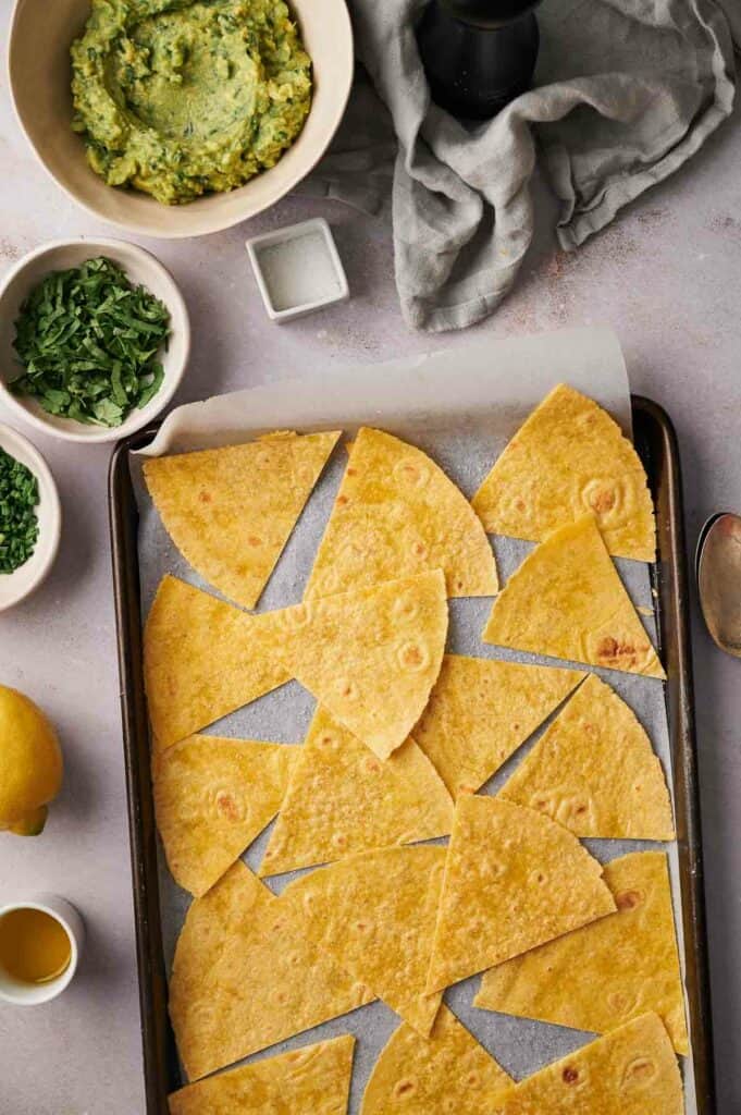 A baking sheet filled with tortillas and a bowl of guacamole.