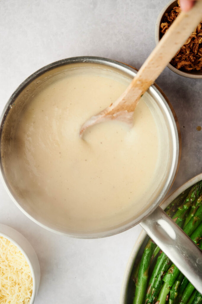 Creamy sauce in a pot with a wooden spoon.