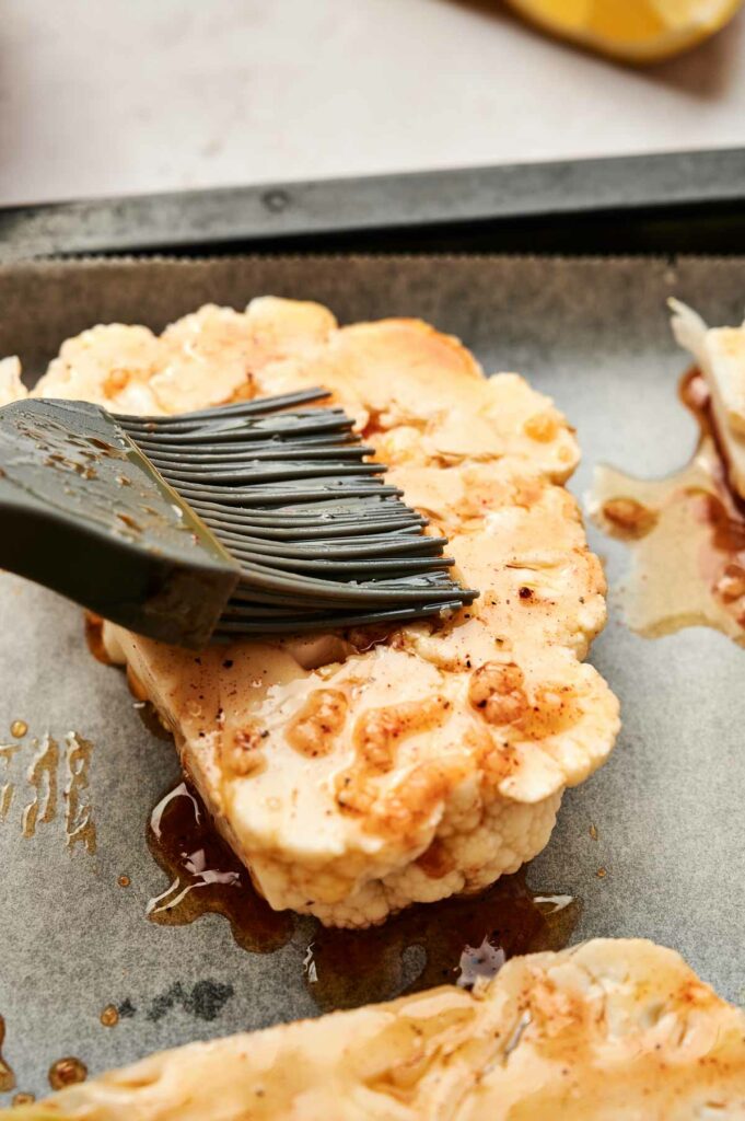 A spatula is being used to garnish the cauliflower from a baking sheet.