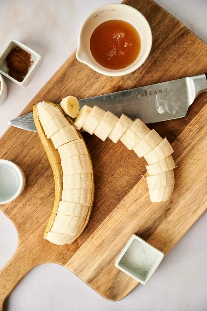Sliced bananas on a cutting board with a knife.