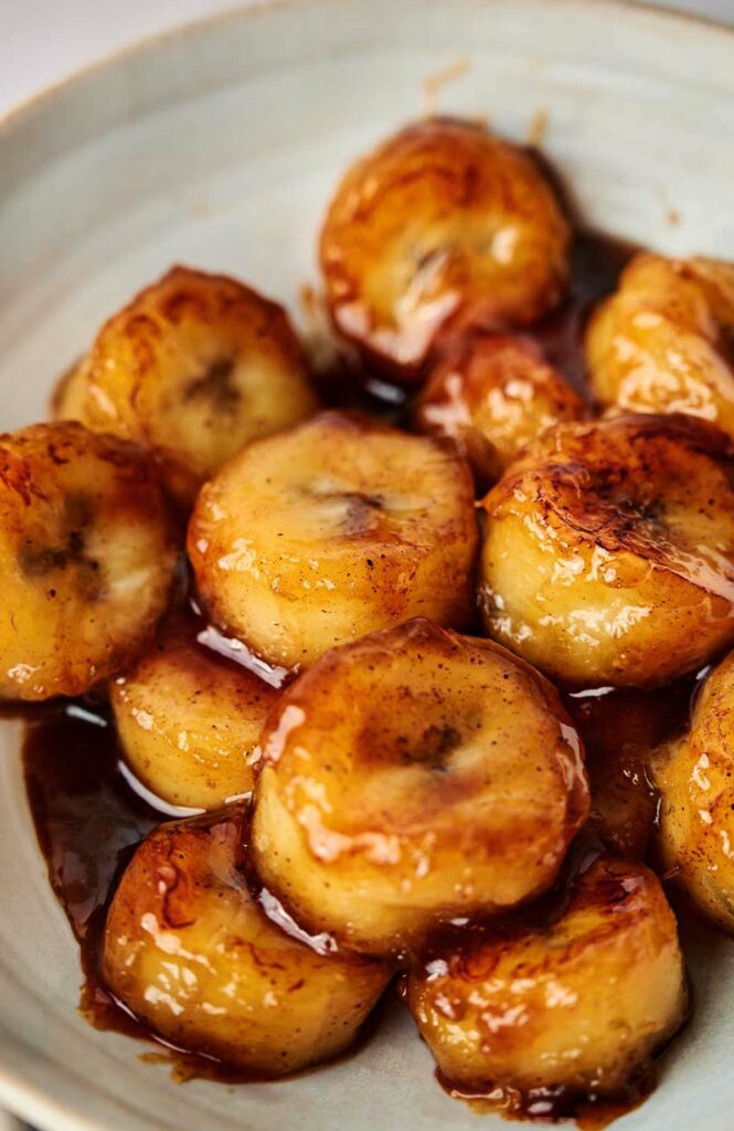 A plate of fried bananas with caramelized sauce on it.