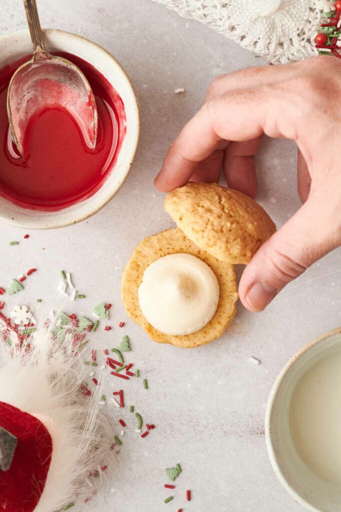 A person is dipping a cookie into a bowl of icing.