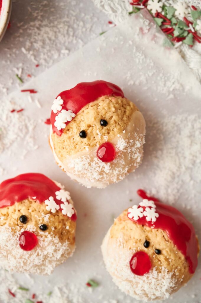 Three santa claus cookies with sprinkles on top.