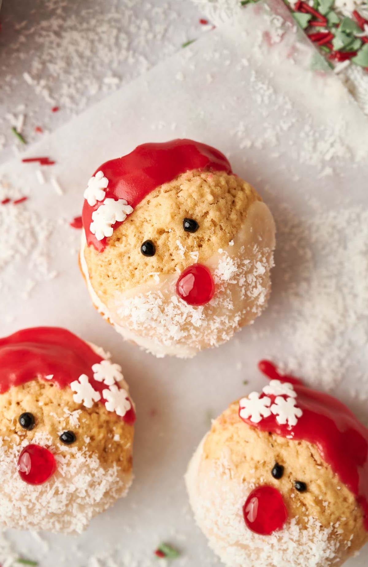 Three santa claus cookies on a baking sheet.