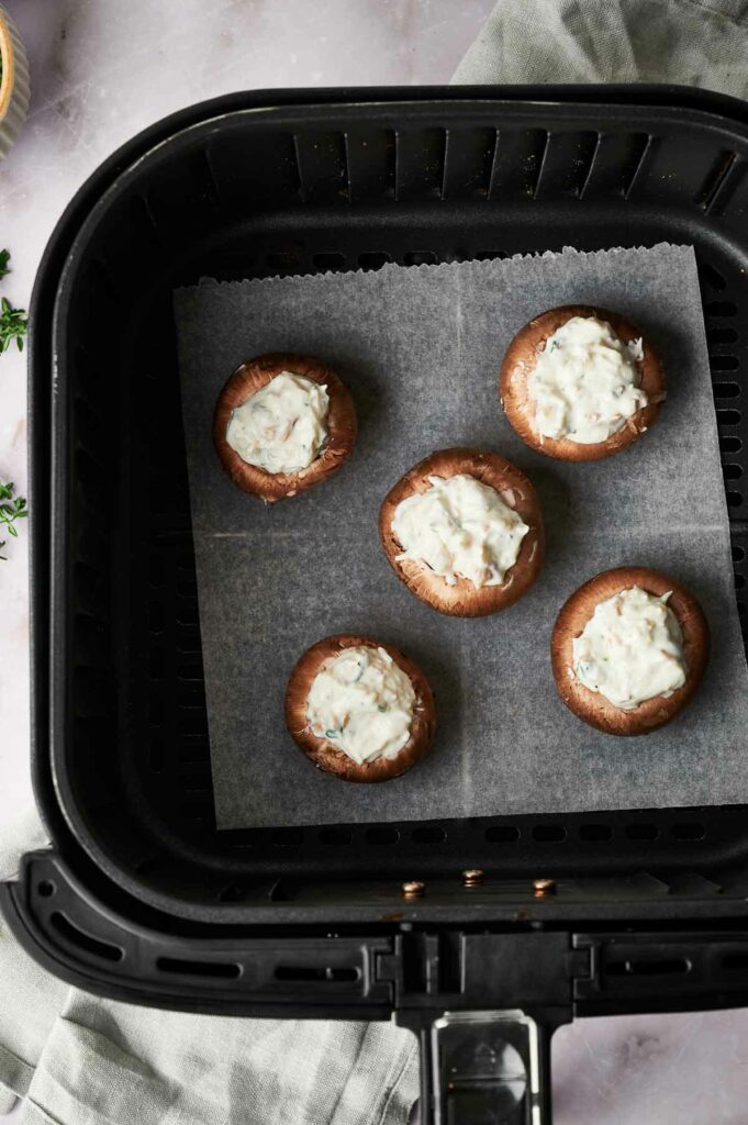 A small air fryer with stuffed mushrooms on it.
