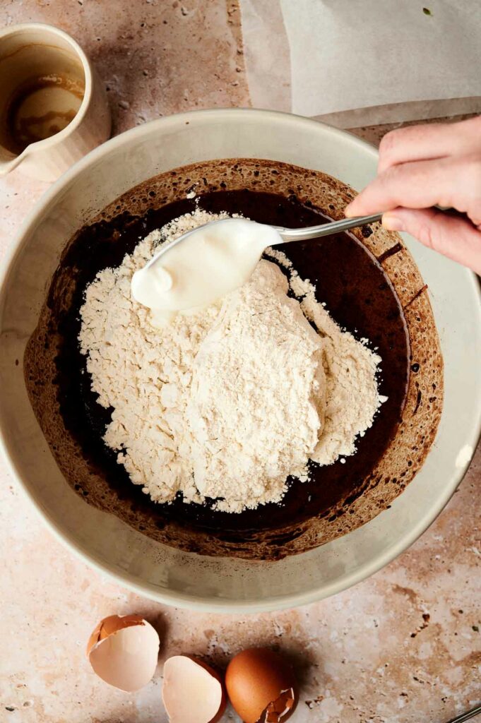 A person mixing the wet and dry ingredients to prepare an air fryer cake.