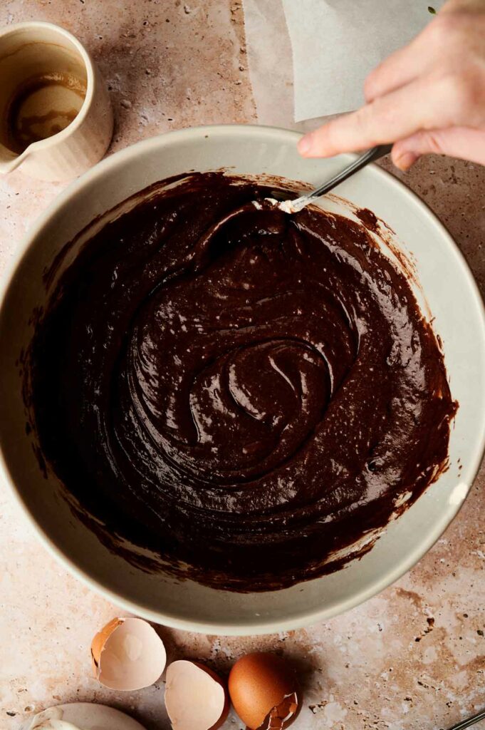 A person whipping up delicious chocolate batter in a bowl.