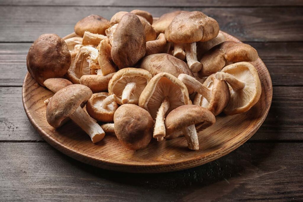 A plate of mushrooms in bowl, on a wooden table.
