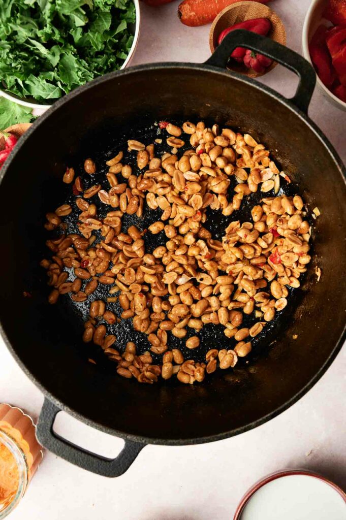 A pot with garlic, onion, red curry paste, and peanuts.