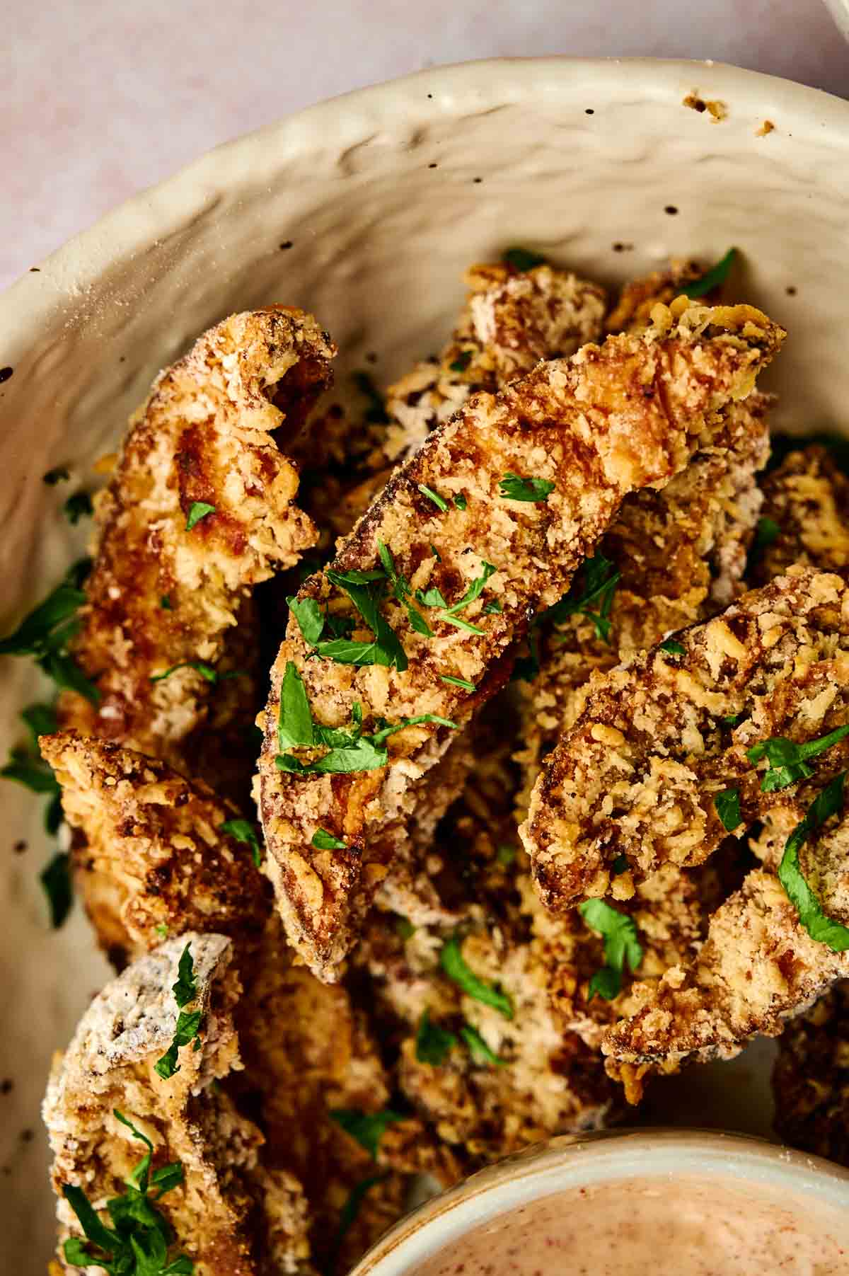 A bowl of delicious portobello mushroom fries with a dipping sauce.