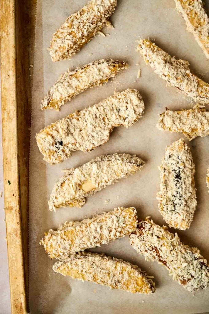 A baking sheet with a tray of breaded portobello mushroom fries.