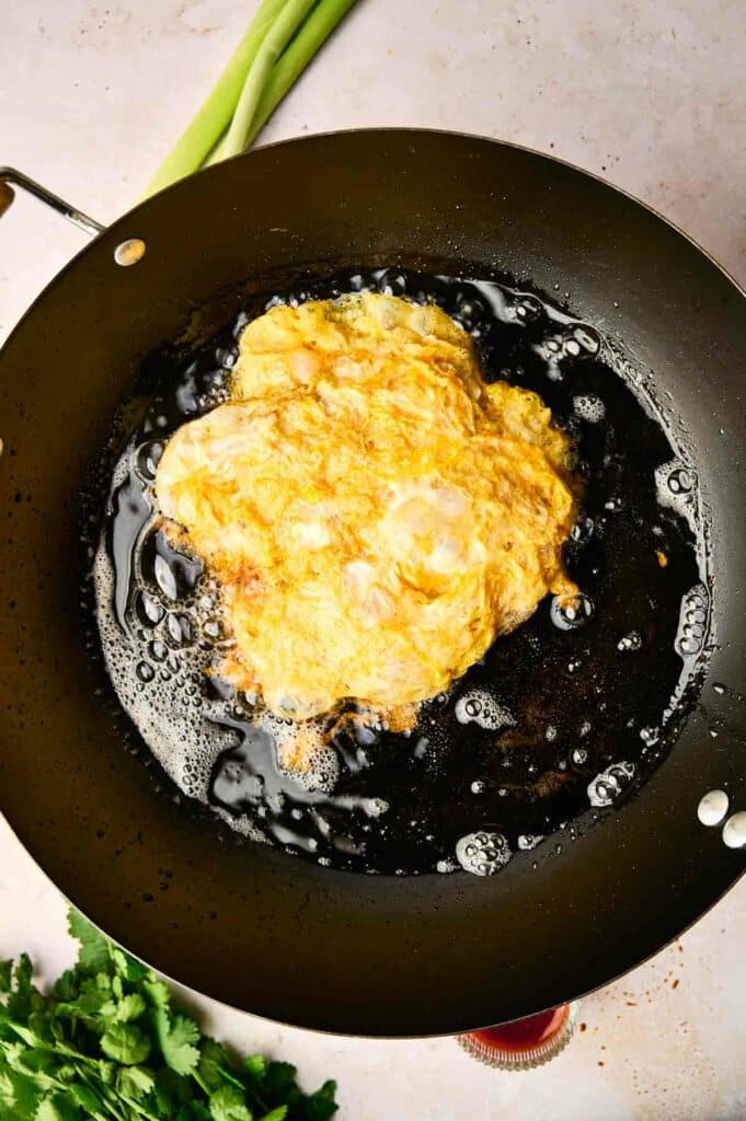 A Thai omelette sizzling in a pan.