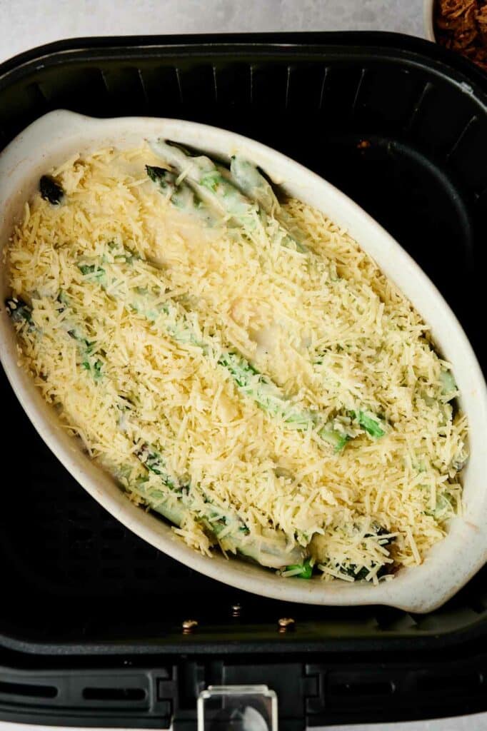 A white dish with an air fryer asparagus and cheese casserole.