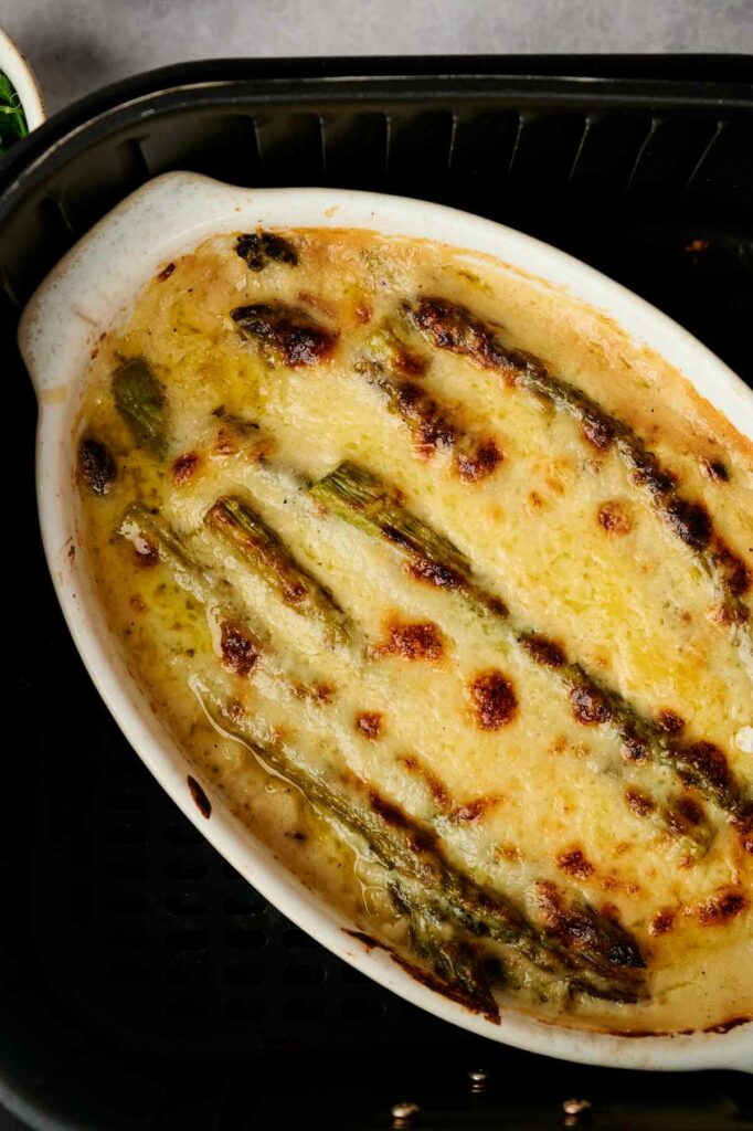 A casserole dish with air fryer asparagus and cheese in it.