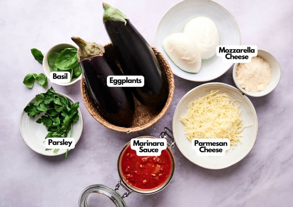 Bowls containing ingredients for eggplant casserole&mdash;eggplants, mozzarella cheese, parmesan, marinara sauce, basil, and parsley&mdash;arranged on a white surface.