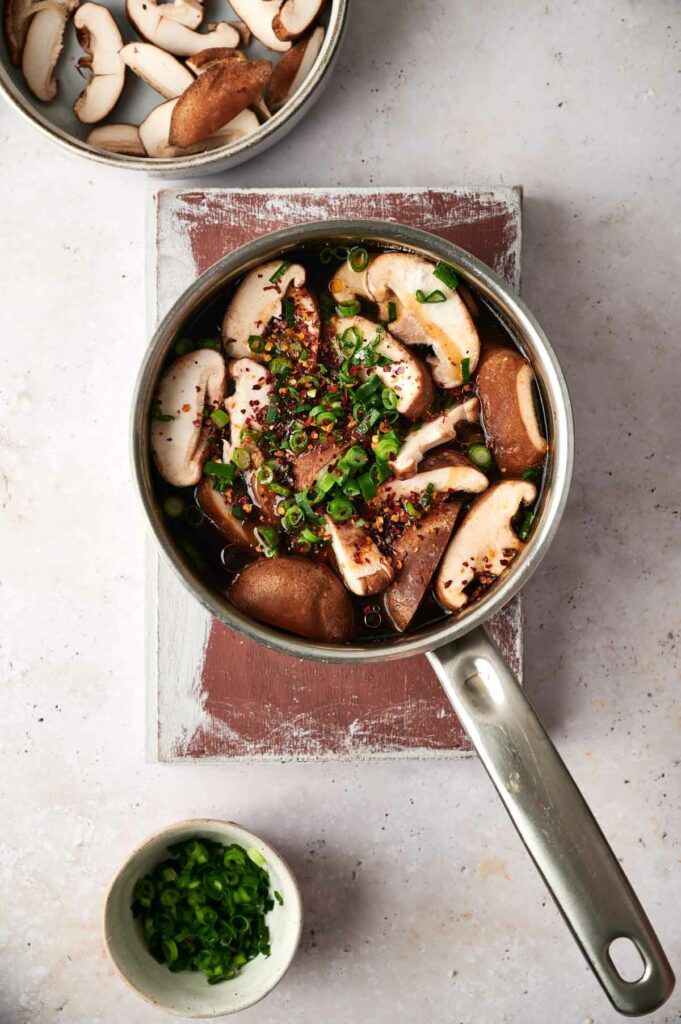 Sauteed mushrooms in a pan on a table with Korean tofu soup.