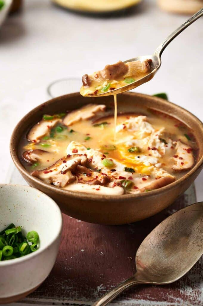 A spoon over a bowl of Korean tofu soup.