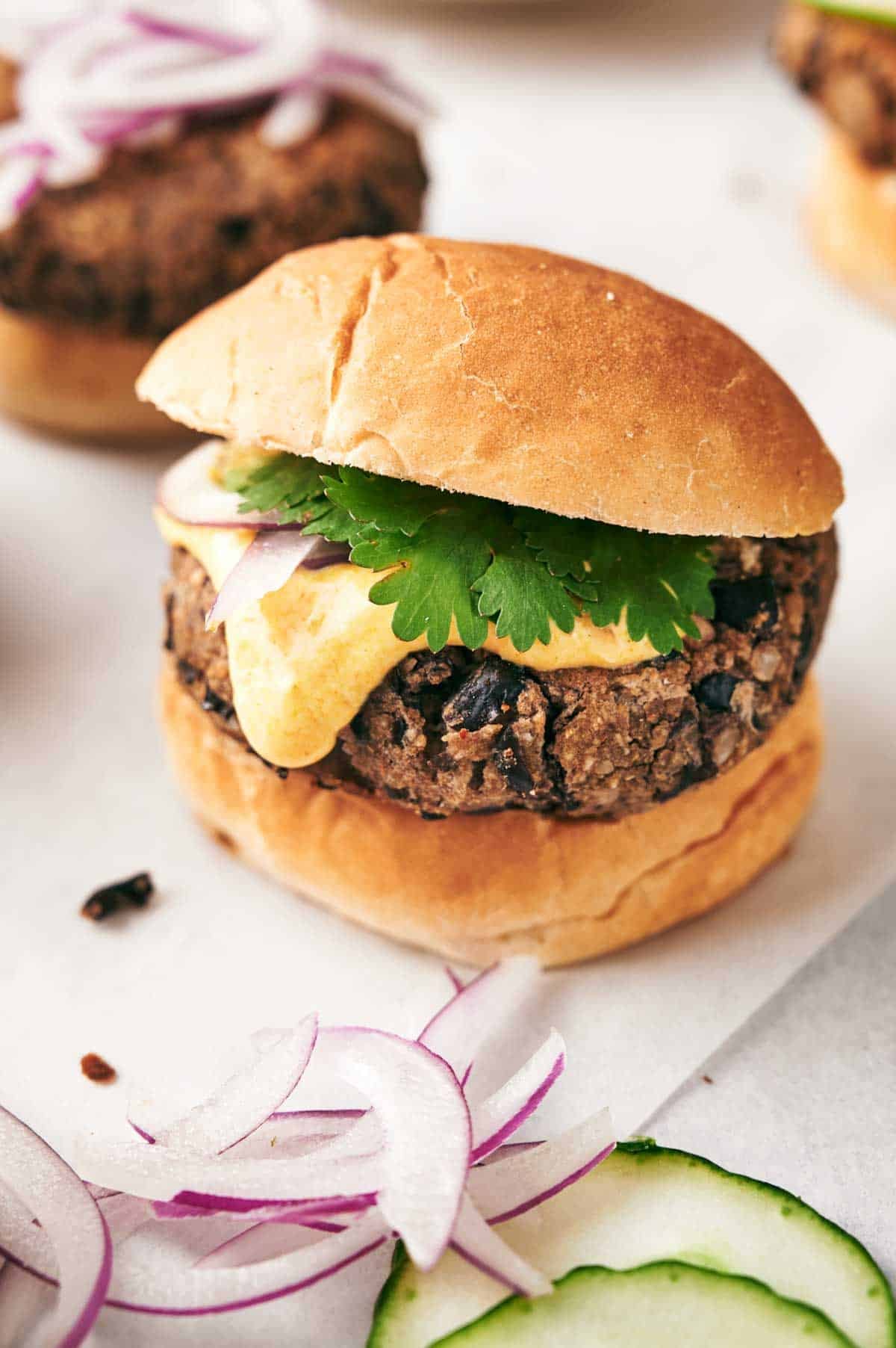 Black bean slider with fresh cilantro and sliced red onions on a bun.