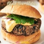 A close-up of a black bean slider garnished with a leaf of parsley.