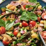 A delightful Pasta Primavera with asparagus, peas, cherry tomatoes, and fresh basil in a blue bowl.