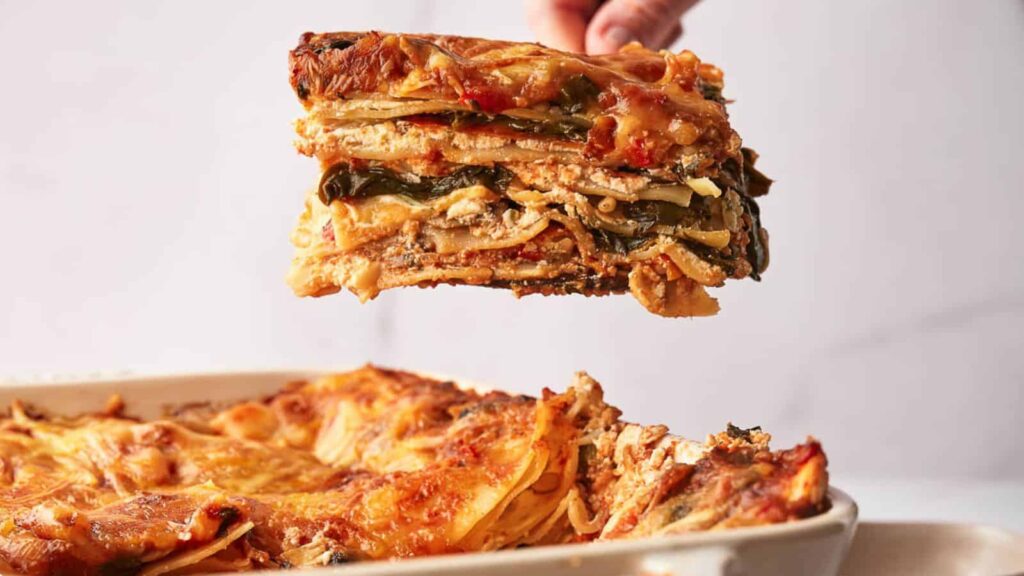 A person serving a slice of layered vegetable lasagna during Thursday feasts you'll love.