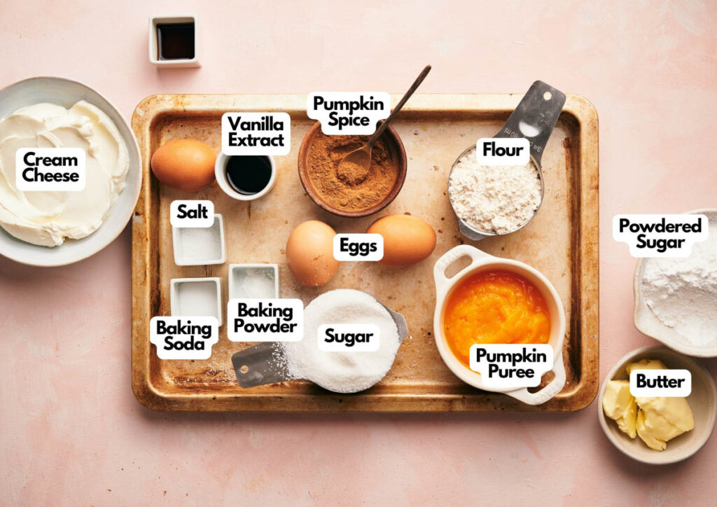 A baking tray with labeled ingredients for pumpkin dessert: cream cheese, vanilla, pumpkin spice, flour, salt, eggs, baking soda, baking powder, sugar, pumpkin puree, powdered sugar, and butter.