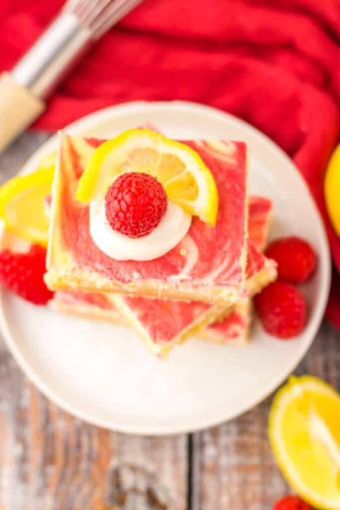 A pile of Raspberry Lemon Cheesecake Bars on a plate. 