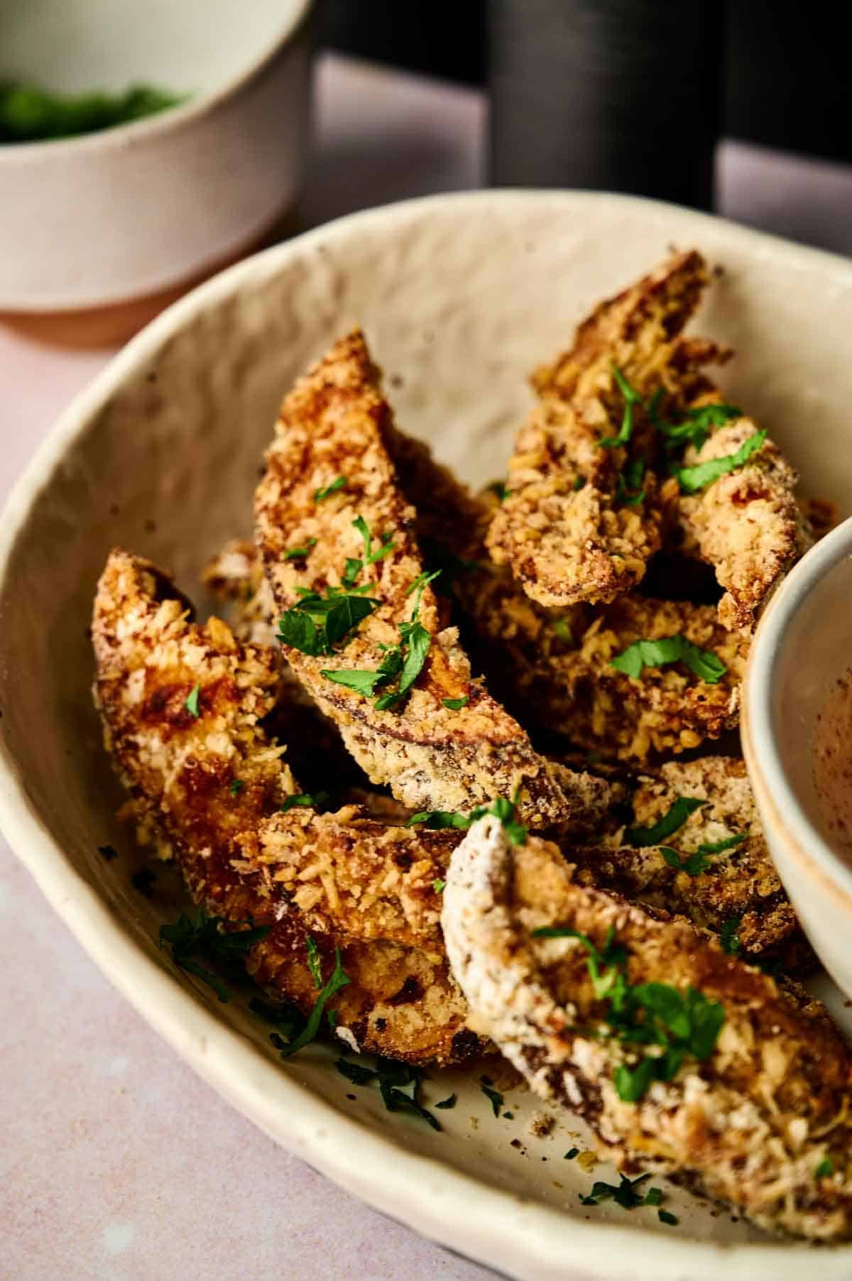 Close-up of a bowl filled with crispy air fryer portobello mushroom fries.