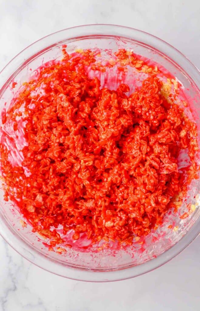 A glass bowl filled with a mixture of bright red ingredients, reminiscent of the vibrant colors found in Patriotic Rice Crispy Treats, shown from above on a light-colored countertop.