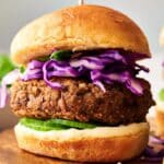 A pair of Veggie Burger Sliders featuring black bean patties, topped with shredded purple cabbage and cucumber slices, served on buns with a layer of mayonnaise.