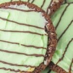 Close-up of Thin Mint Chocolate Cookies with green frosting and chocolate drizzle on top.