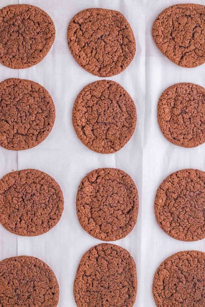 A dozen Thin Mint Chocolate Cookies arranged in rows on a sheet of parchment paper.
