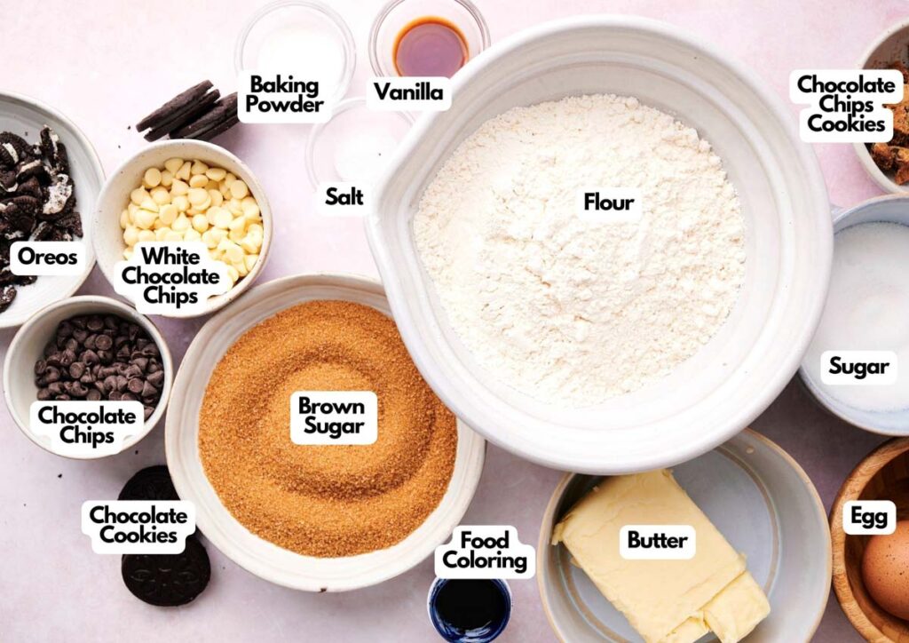 A variety of labeled baking ingredients in bowls, including flour, sugar, brown sugar, butter, egg, chocolate chips, Oreos, vanilla, salt, baking powder, and food coloring—perfect for making Cookie Monster cookies.