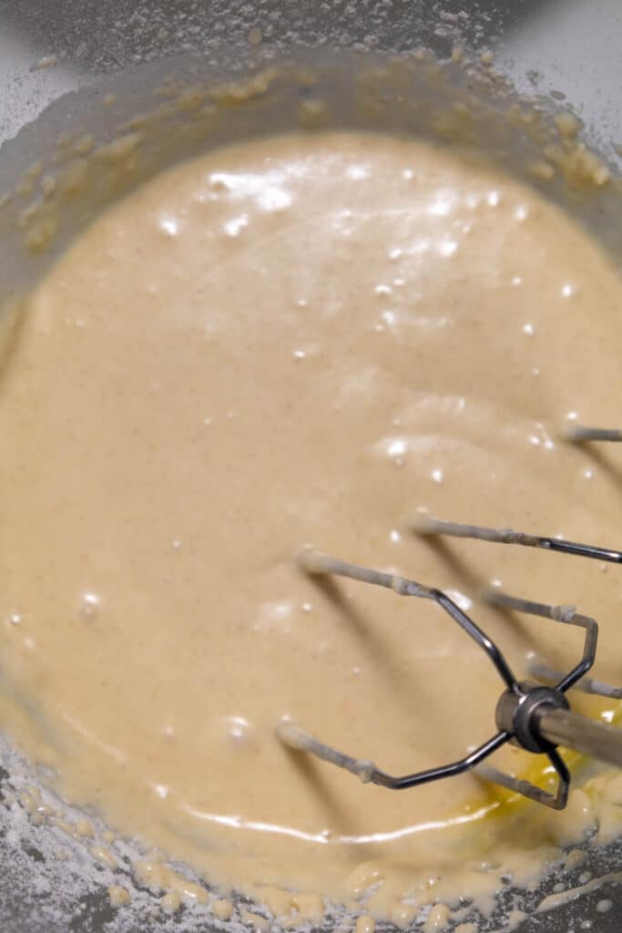 Close-up of smooth batter being mixed with a hand mixer with two beaters in a bowl.