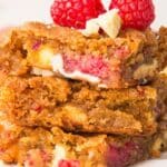 A stack of three decadent Raspberry and White Chocolate Blondies, crowned with fresh raspberries.