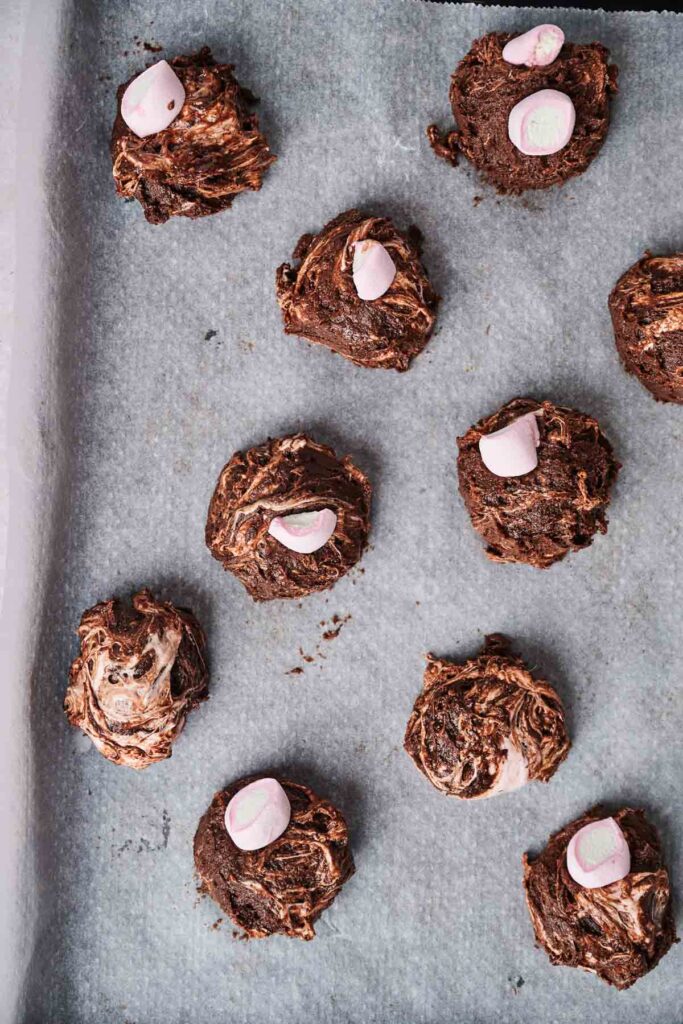 Marshmallow swirl cookies on a parchment-lined baking sheet, ready for baking.